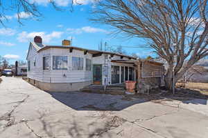 View of front of house with board and batten siding, concrete driveway, and a chimney