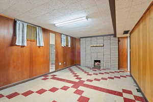 Finished below grade area with wooden walls, a fireplace, and tile patterned floors