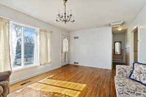 Living area with a textured ceiling, wood finished floors, and visible vents