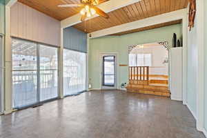 Spare room featuring wooden walls, visible vents, a ceiling fan, wooden ceiling, and beamed ceiling