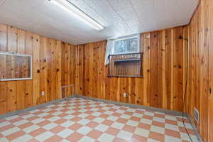 Unfurnished room featuring visible vents, wood walls, and light floors