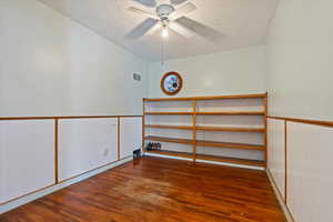 Unfurnished room with a textured ceiling, ceiling fan, dark wood-style flooring, and visible vents