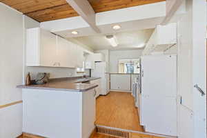 Kitchen with visible vents, white cabinets, light wood-style flooring, freestanding refrigerator, and light countertops