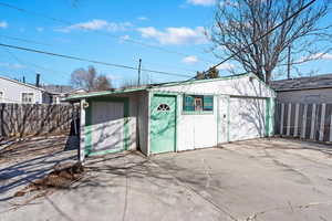 View of outbuilding featuring a garage, an outdoor structure, and fence