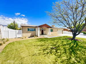 Ranch-style house with driveway, a front yard, brick siding, fence, and an attached garage