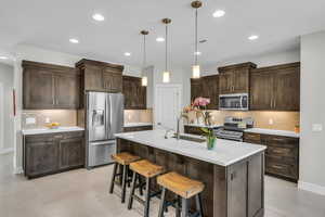 Kitchen featuring dark brown cabinets, visible vents, stainless steel appliances, and a sink