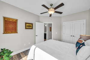 Bedroom featuring a closet, wood finished floors, a ceiling fan, and baseboards