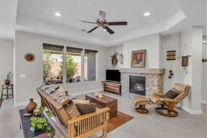 Living area featuring baseboards, a fireplace, a tray ceiling, and recessed lighting