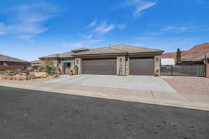 Prairie-style home with an attached garage, fence, driveway, stone siding, and stucco siding