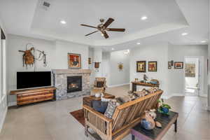 Living room with a tray ceiling, light tile patterned flooring, and baseboards