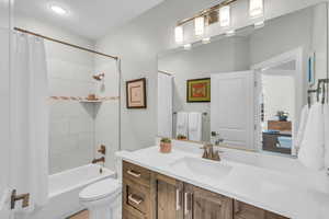 Full bathroom with shower / bathtub combination with curtain, vanity, and toilet