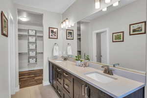 Full bathroom with double vanity, tile patterned flooring, a spacious closet, and a sink