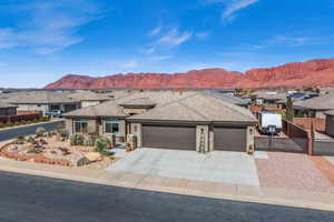 View of front of home featuring stone siding, fence, an attached garage, and a mountain view