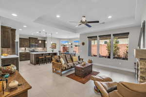 Living room with recessed lighting, a ceiling fan, visible vents, baseboards, and a tray ceiling