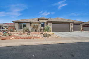 Prairie-style home featuring an attached garage, fence, concrete driveway, stone siding, and stucco siding