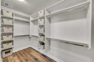 Walk in closet featuring dark wood-style flooring and visible vents