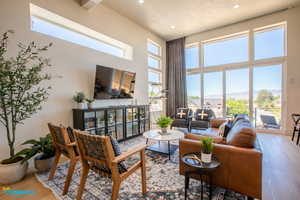 Open living room which includes all furniture, TV, and has large windows leading to the deck to view the valley.