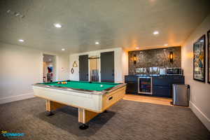 View of the living room that includes the half bathroom door, and locked closet that holds consumable supplies, along with the wet bar and pool table.