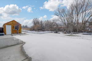 Yard layered in snow with an outbuilding and a storage shed