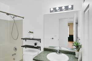 Bathroom with toilet, tub / shower combination, and vanity