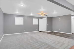 Unfurnished room with dark carpet, dark wood finished floors, ceiling fan, and baseboards