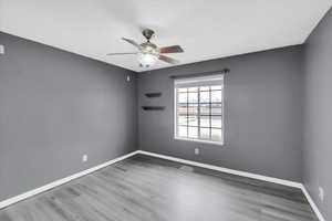 Empty room with ceiling fan, wood finished floors, and baseboards