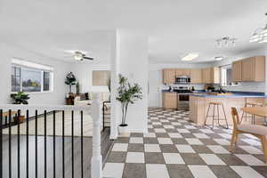 Kitchen featuring a kitchen breakfast bar, a peninsula, stainless steel appliances, light brown cabinetry, and light floors