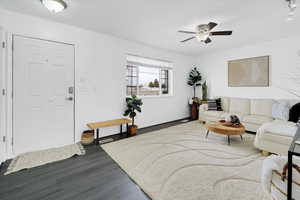 Living area featuring dark wood-type flooring, ceiling fan, and baseboards