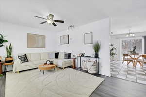 Living room featuring ceiling fan with notable chandelier