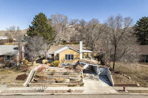 View of front of property featuring driveway, brick siding, and a chimney