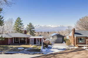 View of front of house featuring an outbuilding, a mountain view, covered porch, brick siding, and concrete driveway