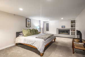 Carpeted bedroom with a tile fireplace, baseboards, and recessed lighting