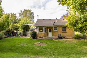 Back of house with brick siding, a lawn, a chimney, and central air condition unit