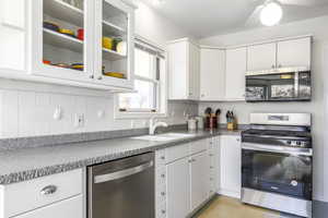 Kitchen with appliances with stainless steel finishes, a sink, white cabinetry, and decorative backsplash