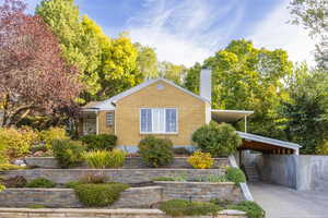 View of front of house featuring a chimney, an attached carport, concrete driveway, and brick siding