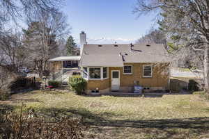 Rear view of property featuring brick siding, a yard, a chimney, and fence