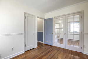 Empty room with ornamental molding, french doors, baseboards, and dark wood-style flooring