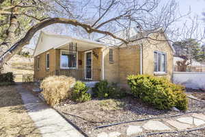 Bungalow-style home featuring brick siding, a porch, fence, and a gate