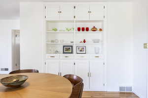 Dining room featuring light wood-type flooring, baseboards, built in shelves, and visible vents