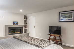 Carpeted bedroom with baseboards, a tiled fireplace, and recessed lighting