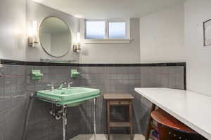 Bathroom featuring a sink, tile walls, and wainscoting