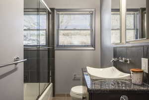 Full bath featuring bath / shower combo with glass door, vanity, toilet, and tile patterned floors