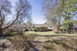 Rear view of house featuring a yard and a chimney