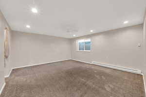 Carpeted spare room with recessed lighting, baseboards, and baseboard heating