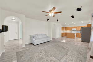 Unfurnished living room with arched walkways, recessed lighting, visible vents, a ceiling fan, and baseboards