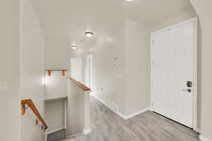 Corridor with baseboards, visible vents, and an upstairs landing