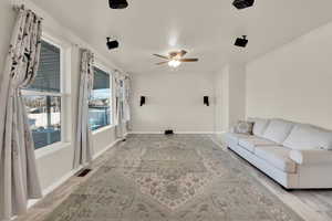 Unfurnished living room featuring a ceiling fan, visible vents, and baseboards