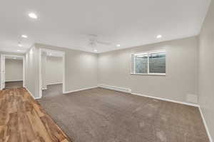 Carpeted empty room with a baseboard heating unit, recessed lighting, and baseboards