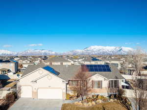 View of front of home featuring a residential view, a mountain view, driveway, and solar panels