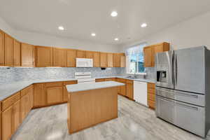 Kitchen featuring recessed lighting, white appliances, a sink, a center island, and decorative backsplash